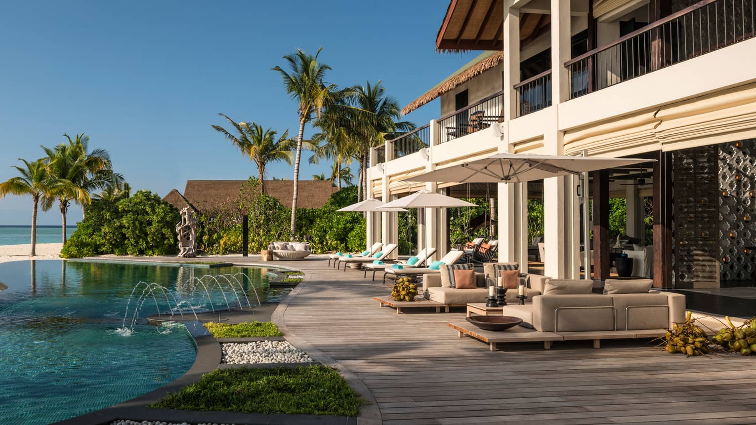 Swimming pool, wood patio under two-storey villa, palm trees