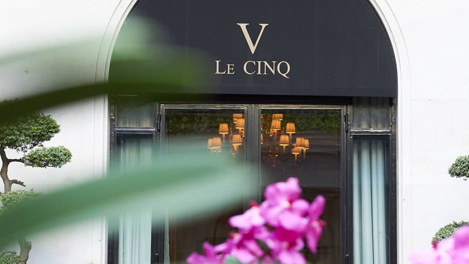 Le Cinq awning over entrance past purple flowers