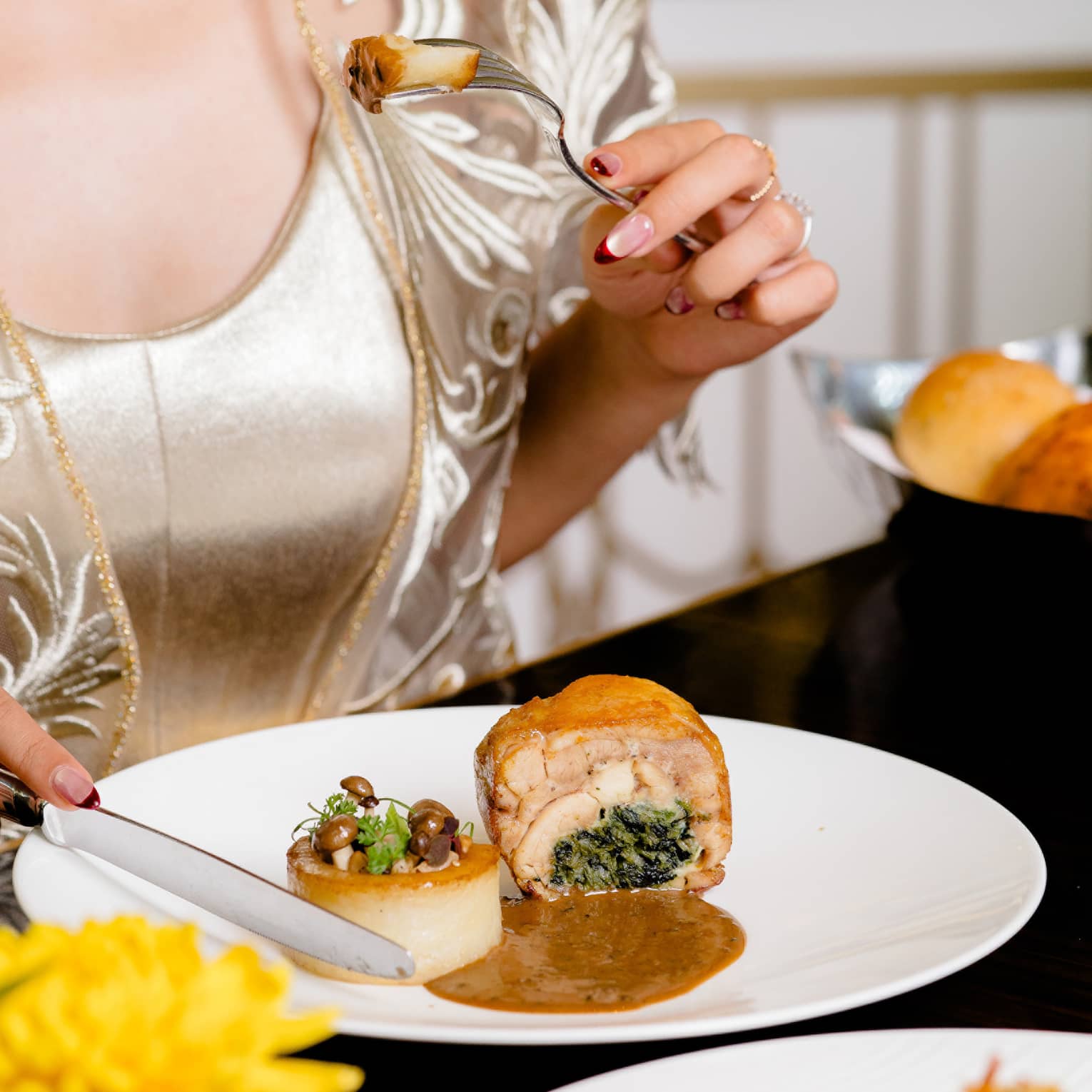 Woman in gold dress eats at fine dining restaurant