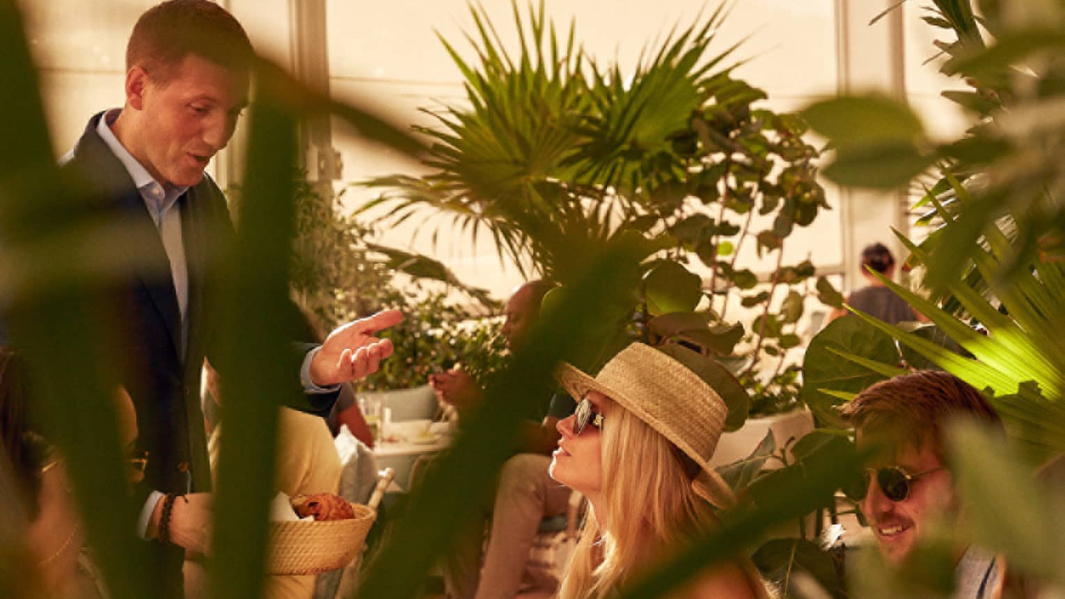 A woman being served food in a covered eating area with plants.