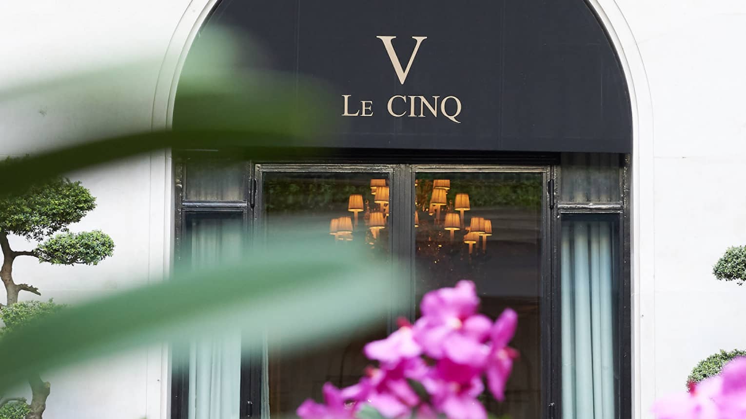 Le Cinq awning over entrance past purple flowers