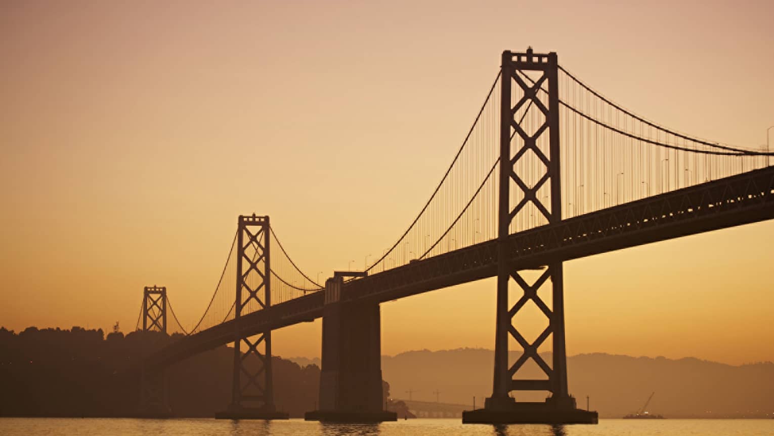 Silhouette of Golden Gate Bridge against an orange sunset 