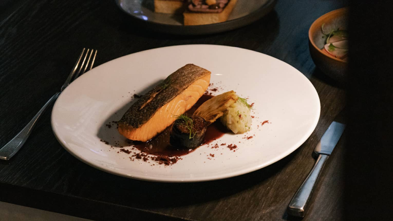 Pan-roasted organic salmon with fennel, roasted figs and Sauce Meurette served on a white plate