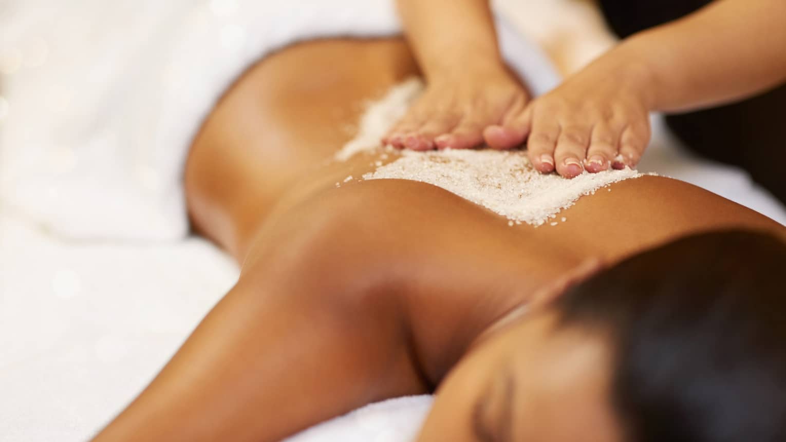 A young woman receives an exfoliating treatment at the spa