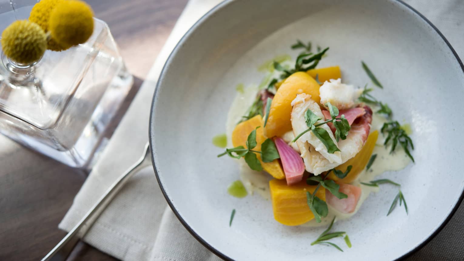 Beet & Dungeness Crab Salad on white plate garnished with tarragon