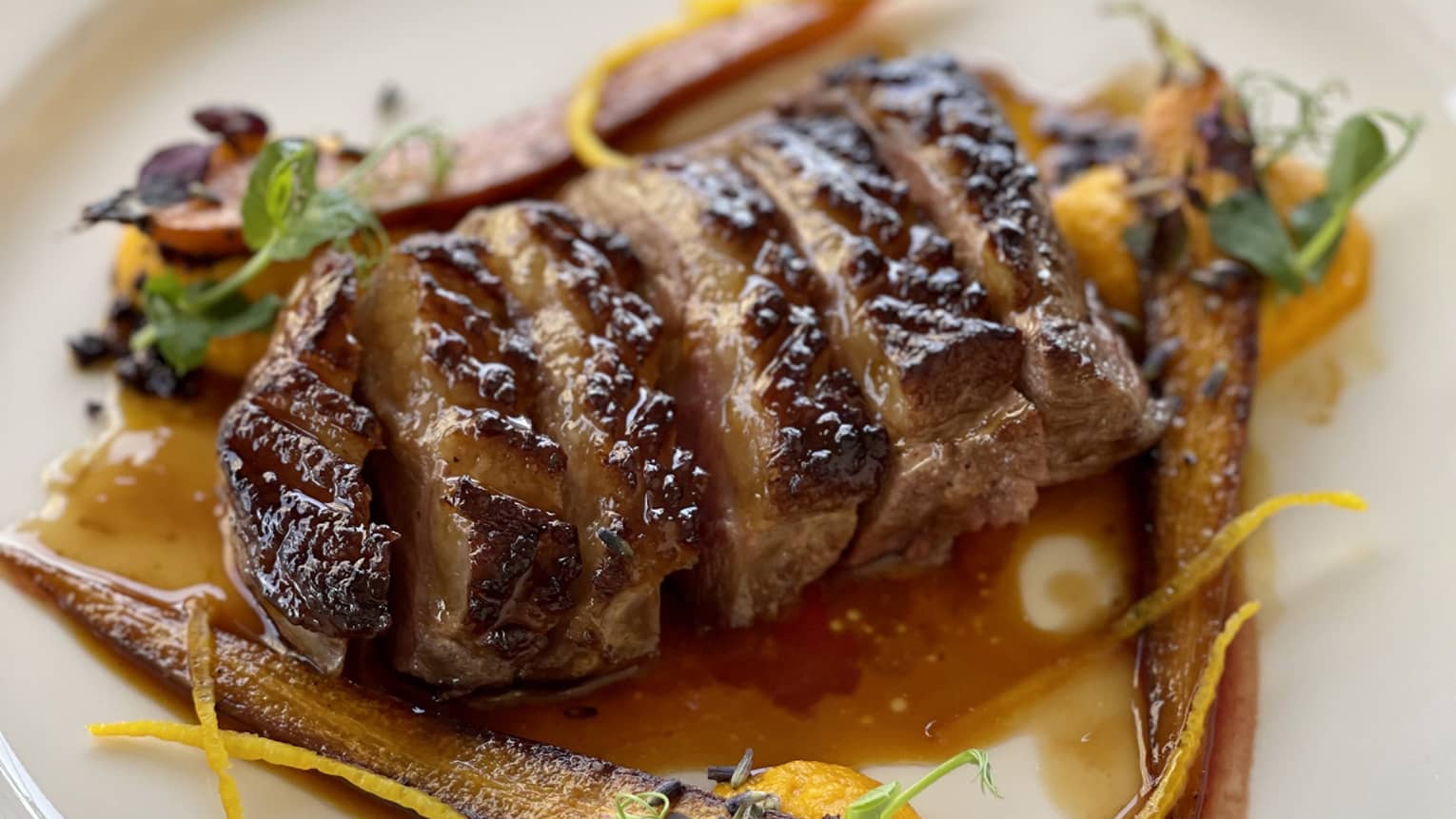 Duck breast with orange glaze, carrot pur�e and lavender served on a white plate