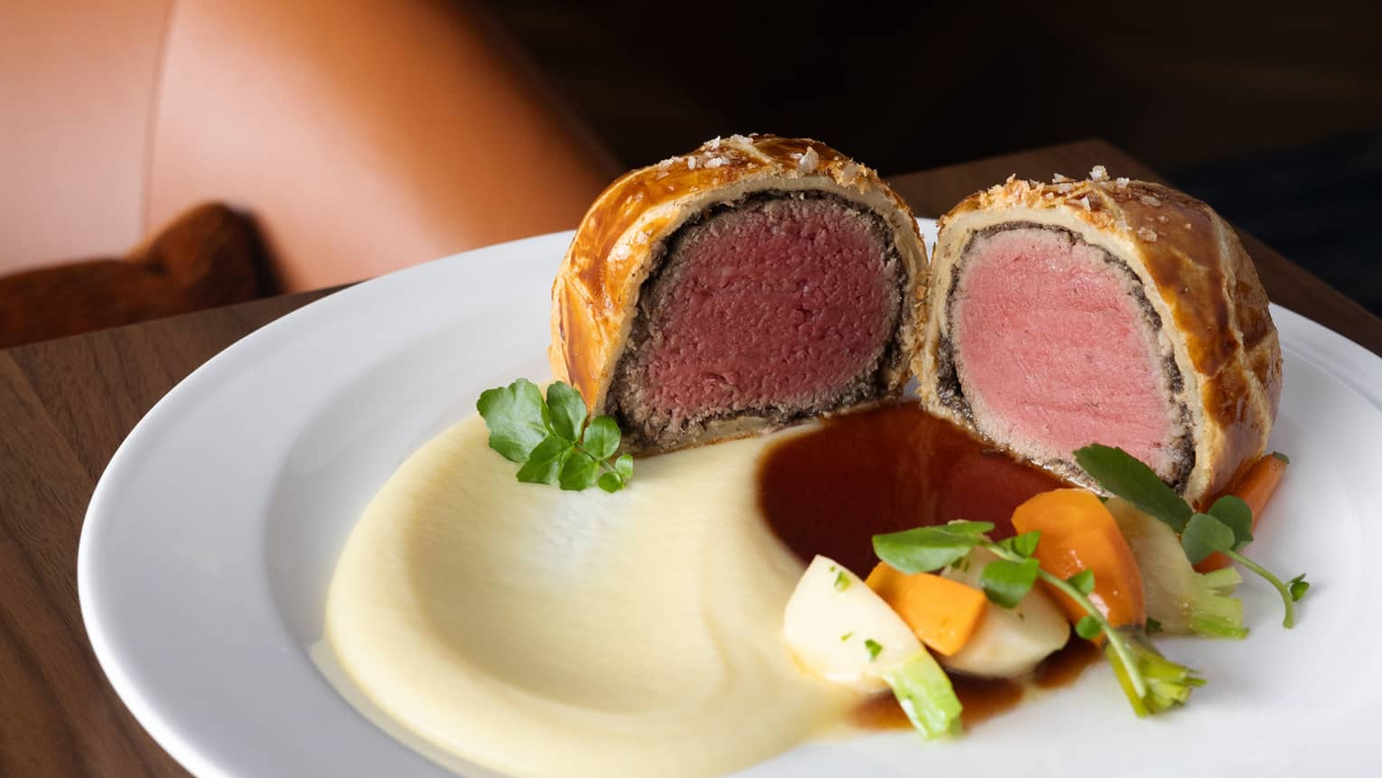 Beef wellington cut in half with vegetables on the side.