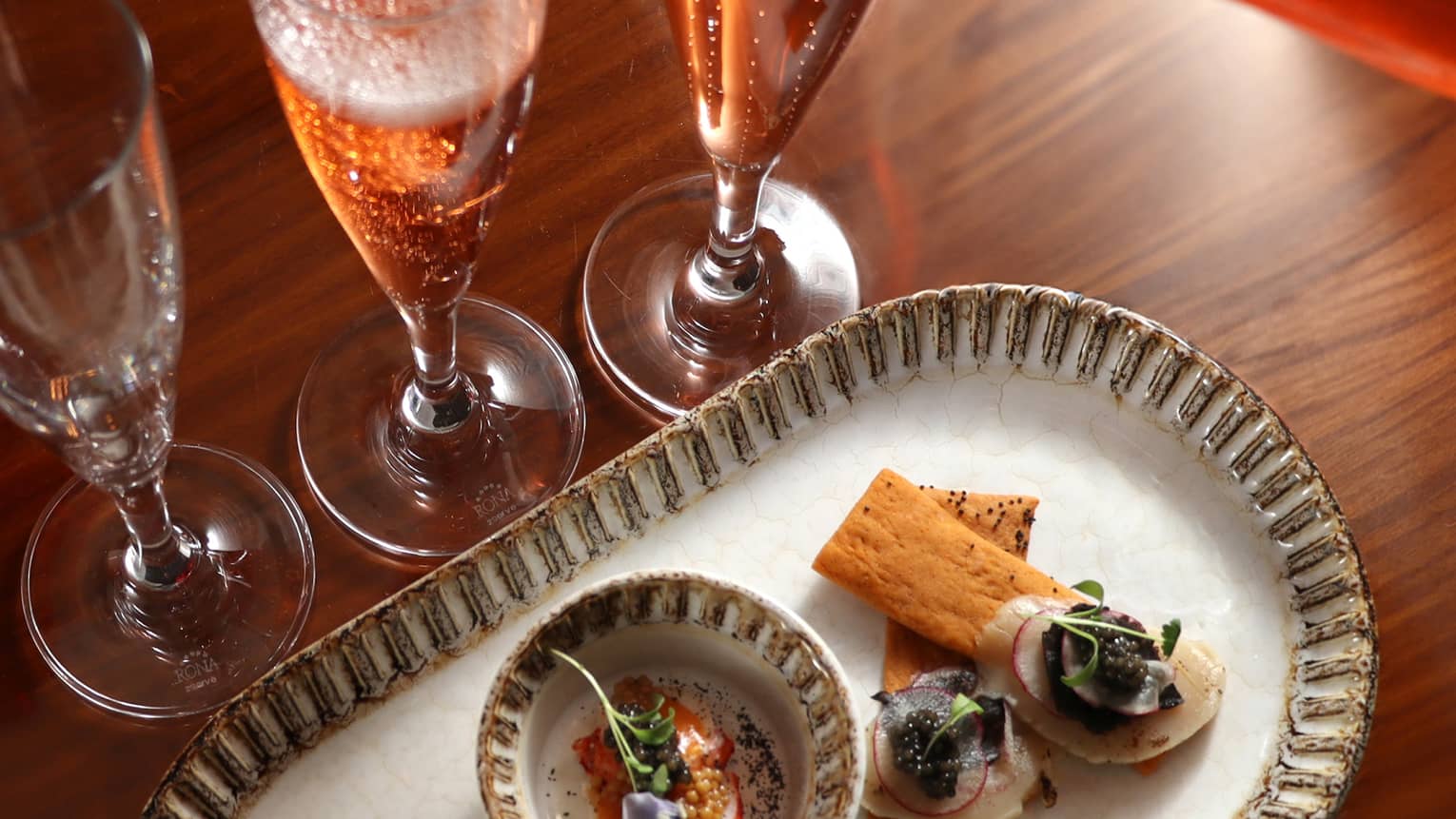 Champagne being poured into a glass beside a food dish