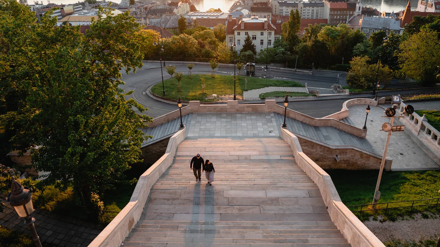 View of a city at sunset from atop steps of a hotel