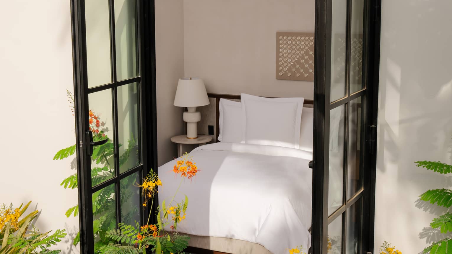 Look into a luxury resort bedroom from outside the window, with flowers