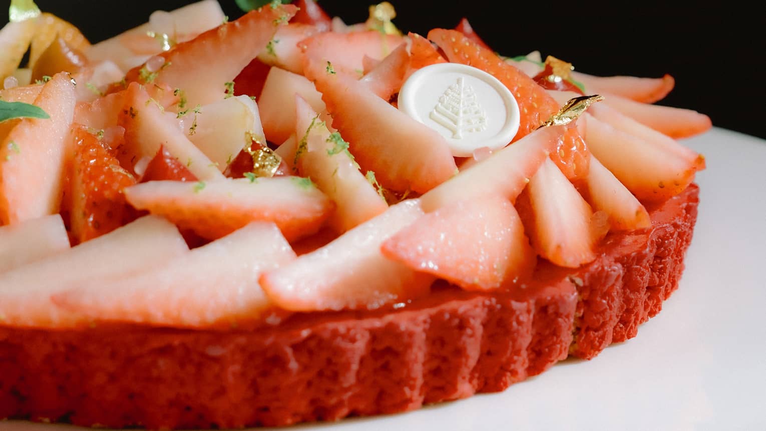 A strawberry tart on a white pedestal cake plate.