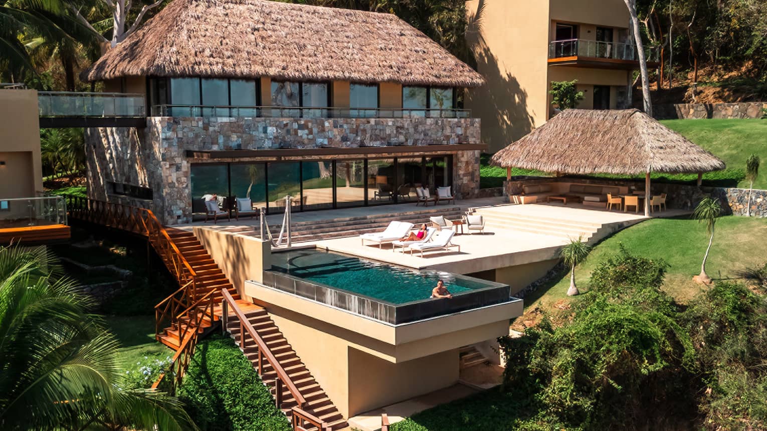 A person in infinity pool of private residence in tropical location