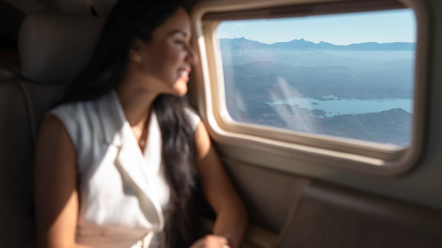 A woman looks out a plane window