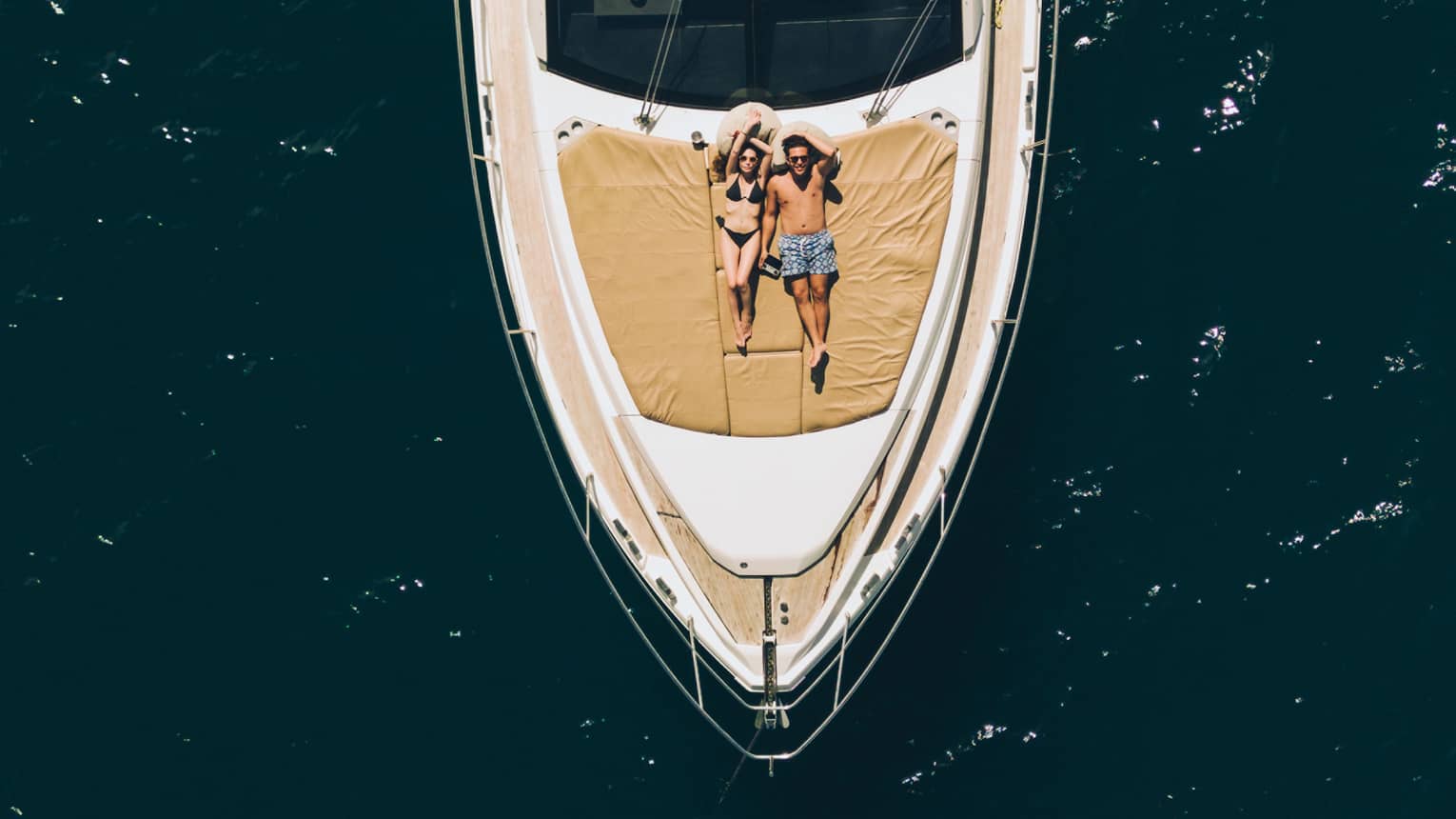 Aerial view of couple relaxing on the front of a large boat