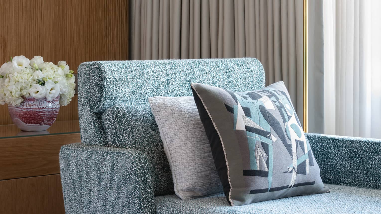 Close-up of blue chaise longue beside beige curtained window, standing floor lamp with white shade