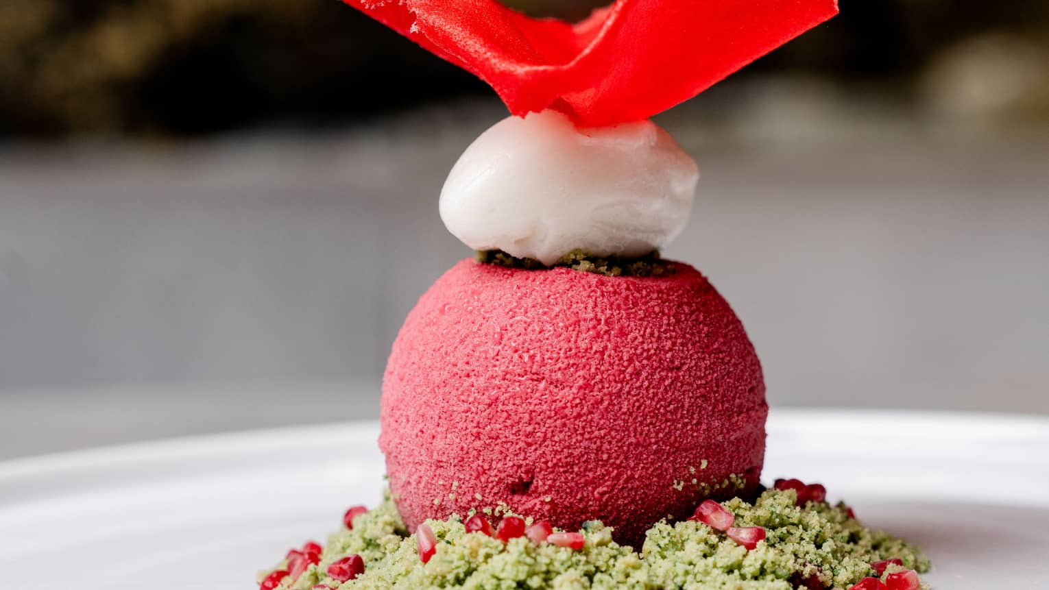 A raspberry dessert on a plate with matcha streusel