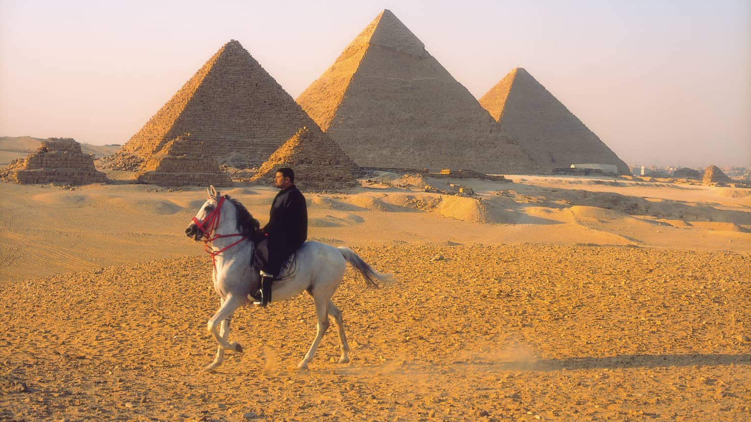 Horseman riding by pyramids