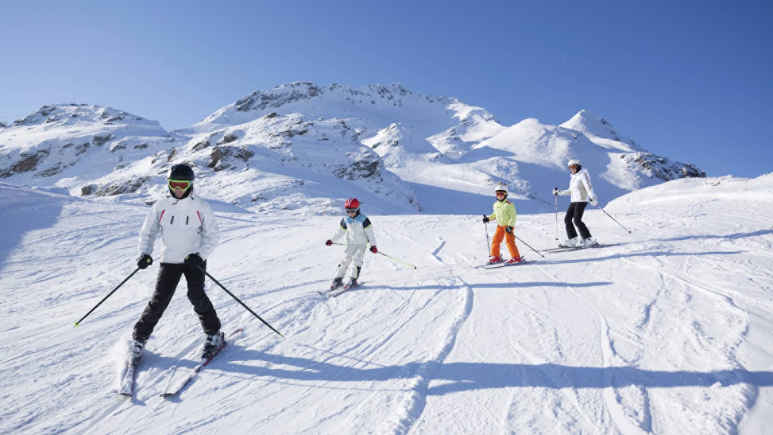 Family skis down snowy mountain