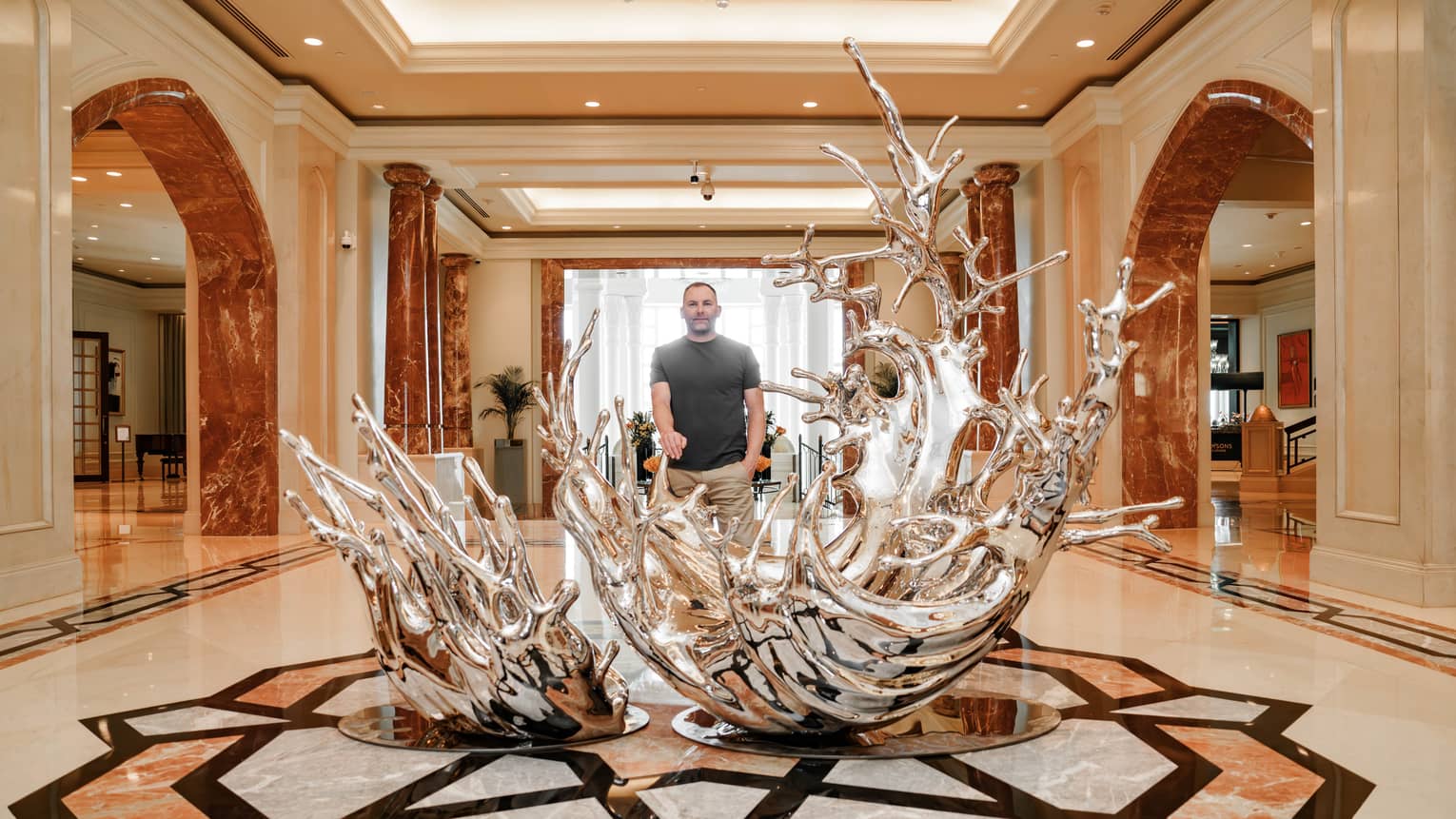 Kinetic Drop silver sculpture with artist Dan Pearce standing behind it