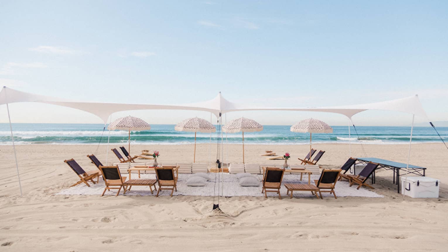 A tent with umbrellas and lounge chairs on a beach