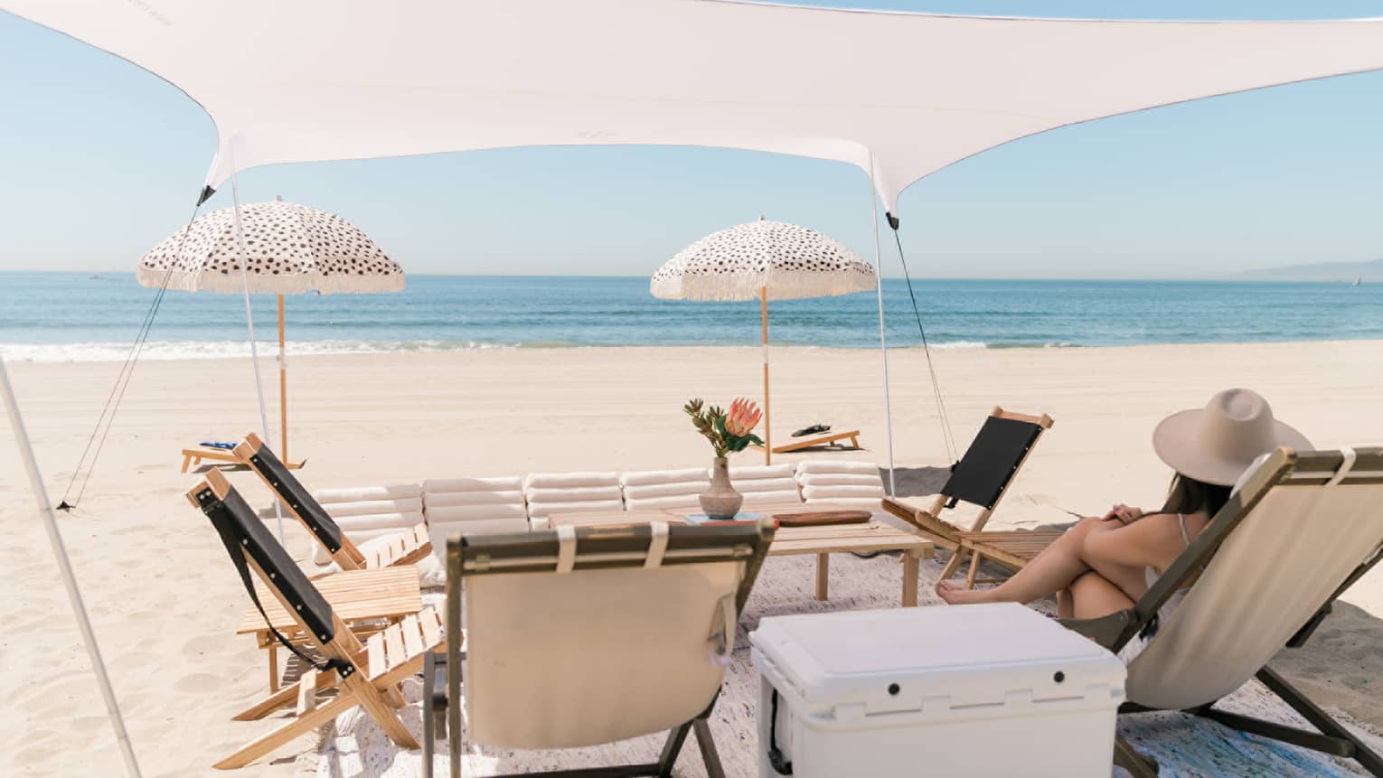 Lounge chairs and a cooler under a tent on the beach