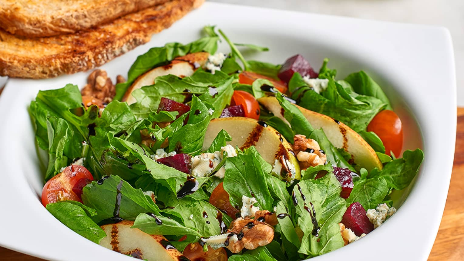 Salade Parisienne dish with green lettuce, grilled chicken slices, tomato, crumbled goat cheese