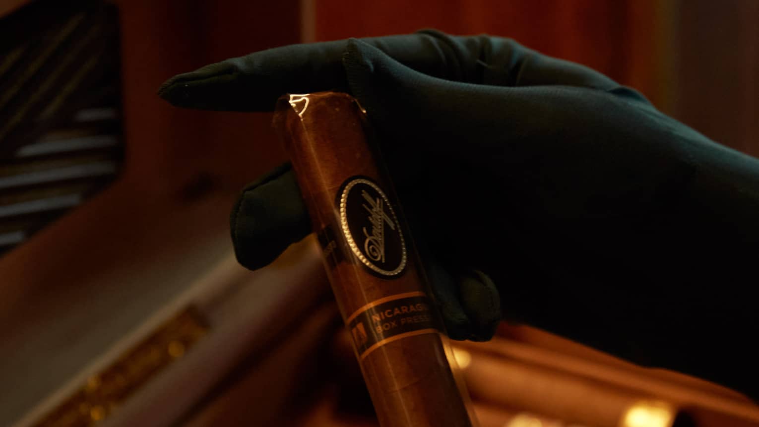 A person in gloves holding a cigar.
