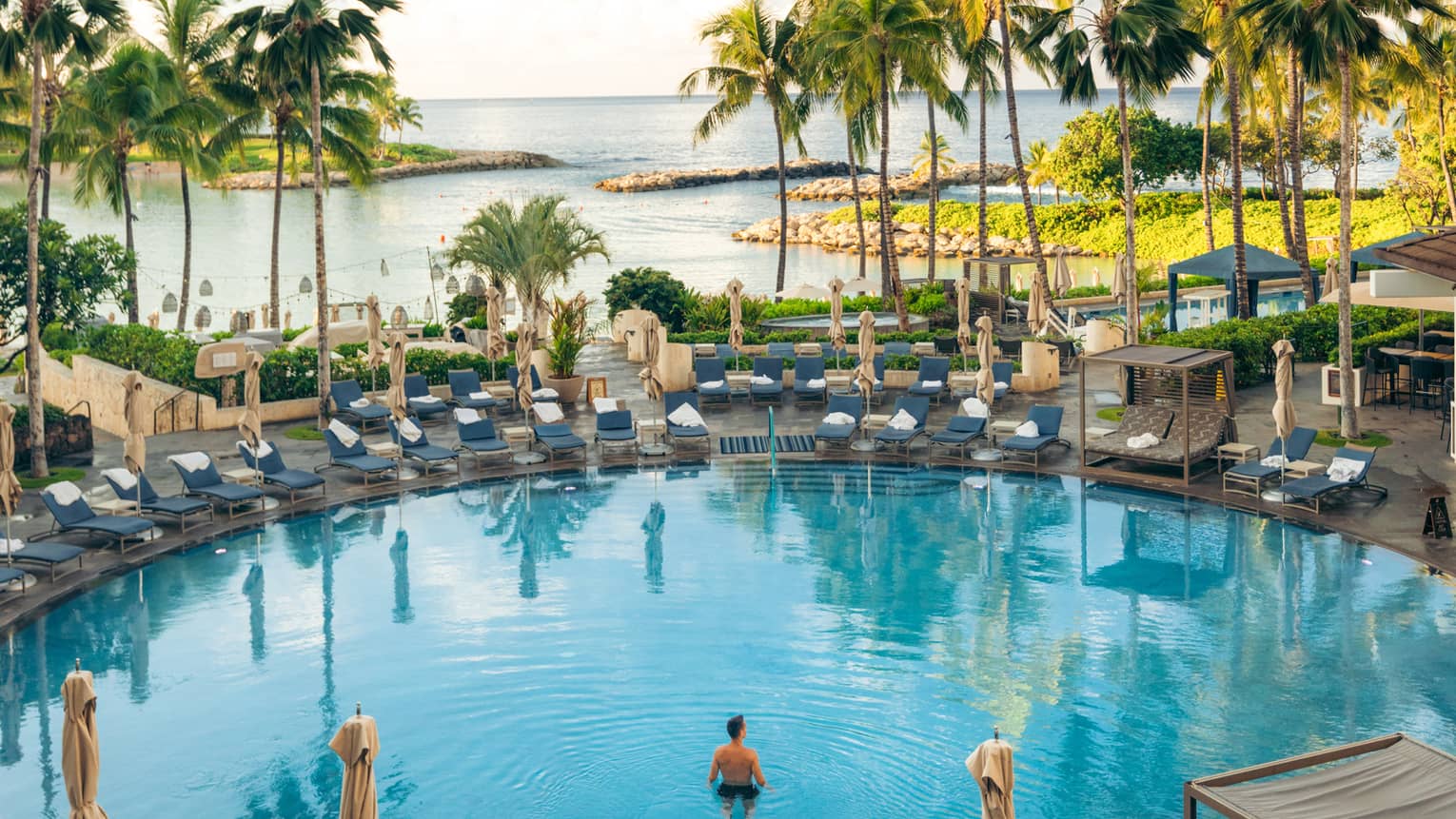 Large circular resort pool with view of tropical lagoon