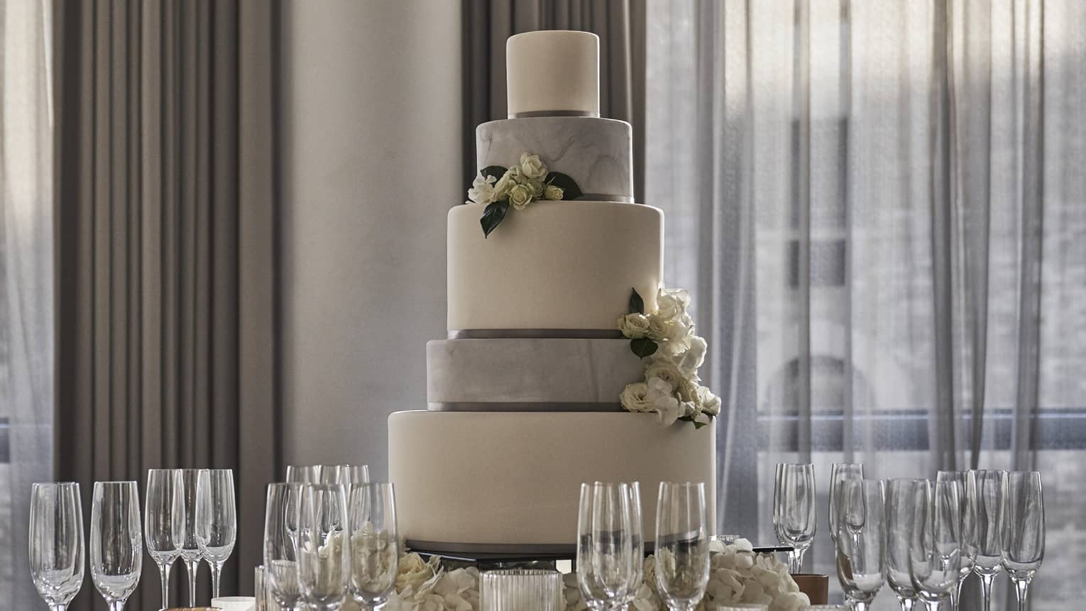 Tiered wedding cake on round banquet table with Champagne glasses