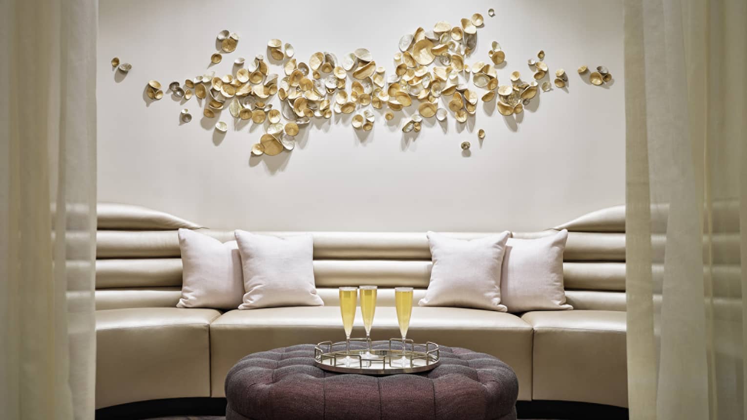 Gold couch and ottoman with champagne on top.