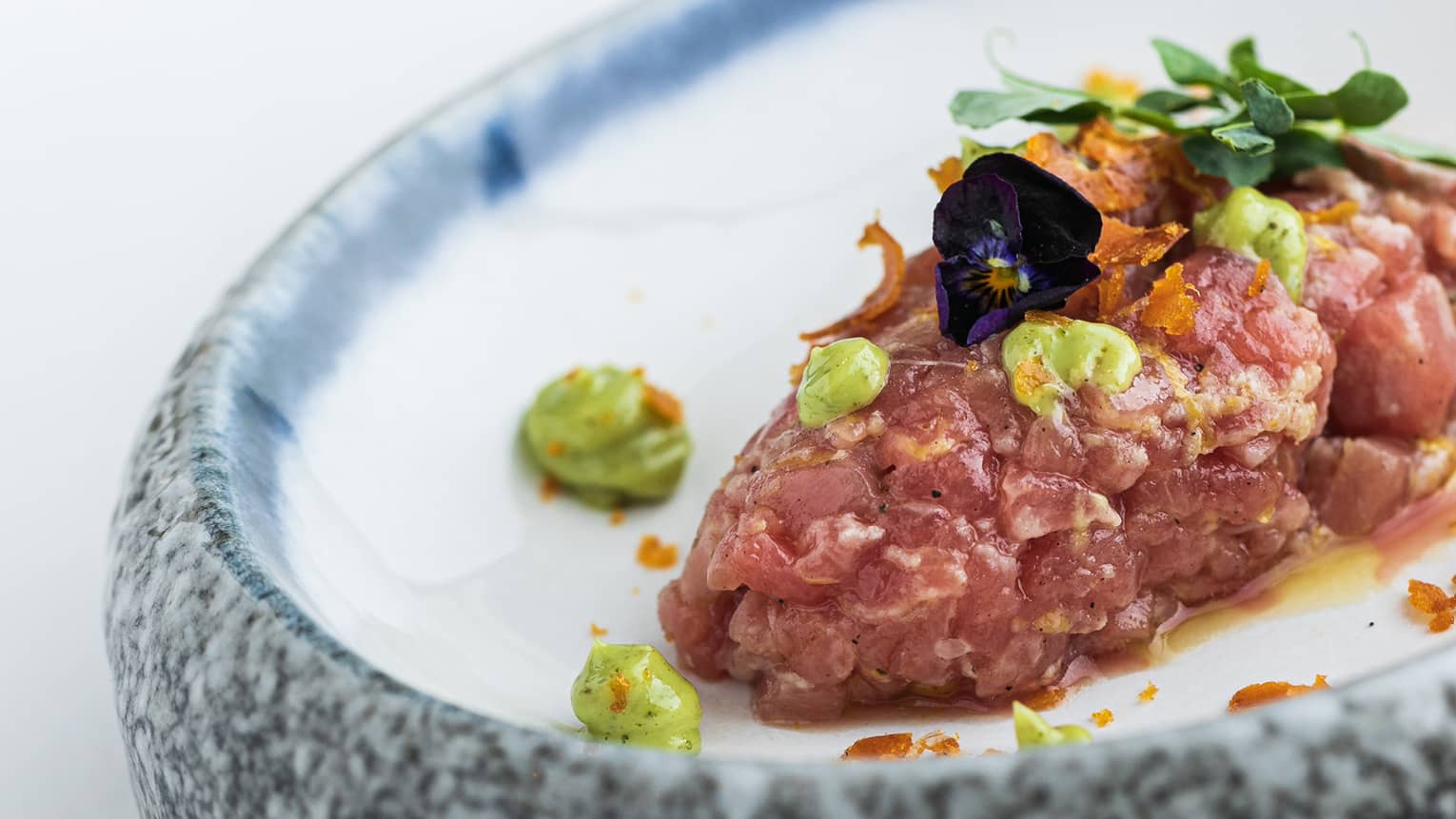Tuna in a bowl with greens on it.