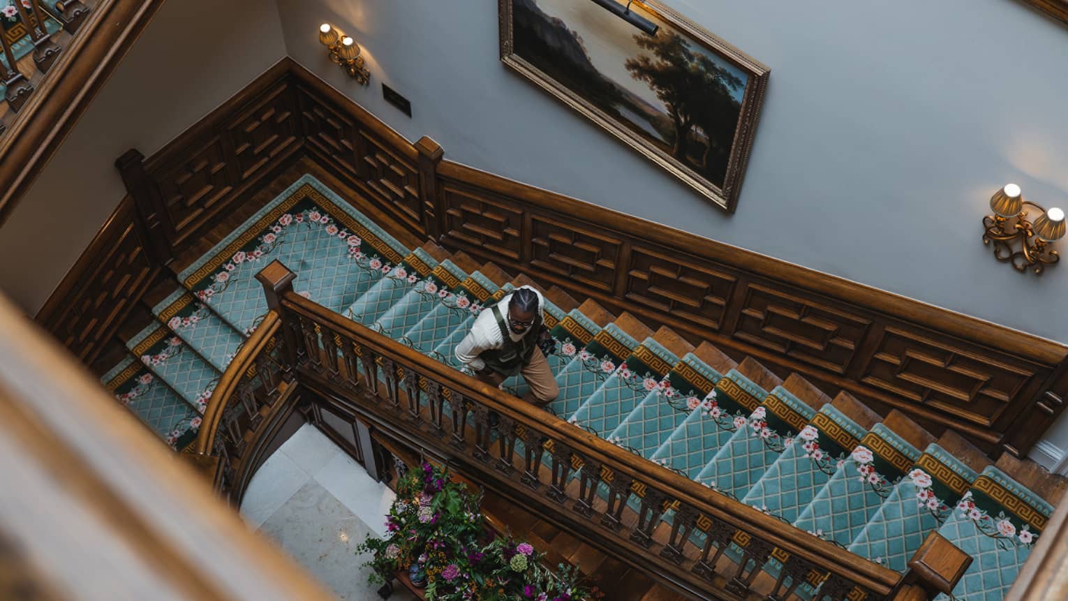 A rectangular wood spiral staircase with a teal blue runner