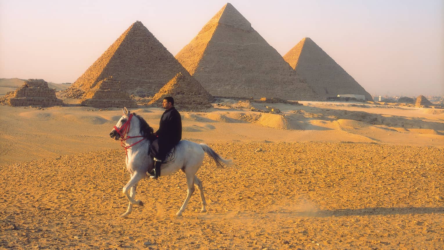Horseman riding by pyramids