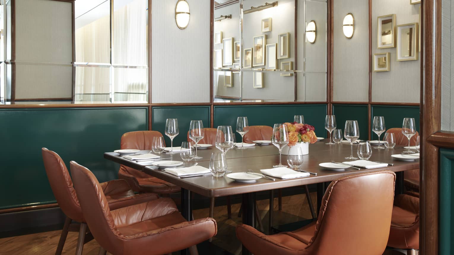 Private dining room with mirrored walls, dark green accents and a rectangular table with brown-leather seats