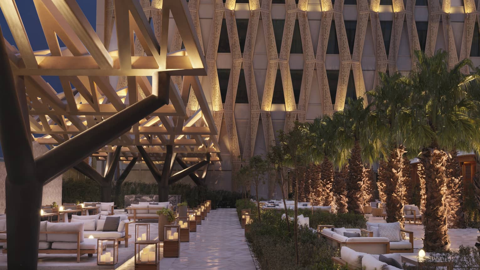 Illuminated outdoor patio sitting area with architectural designs on surround building.