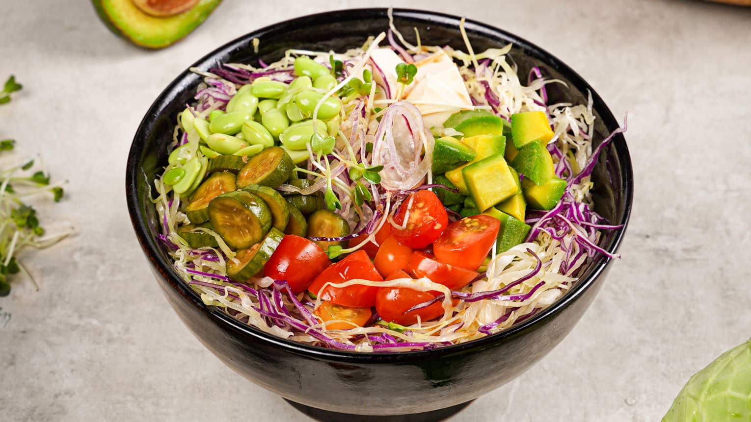 Poke bowl topped with colourful vegetables including tomatoes, edamame and avocado