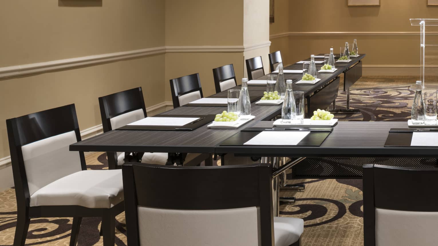 Meeting room with modular boardroom tables lines with white chairs 