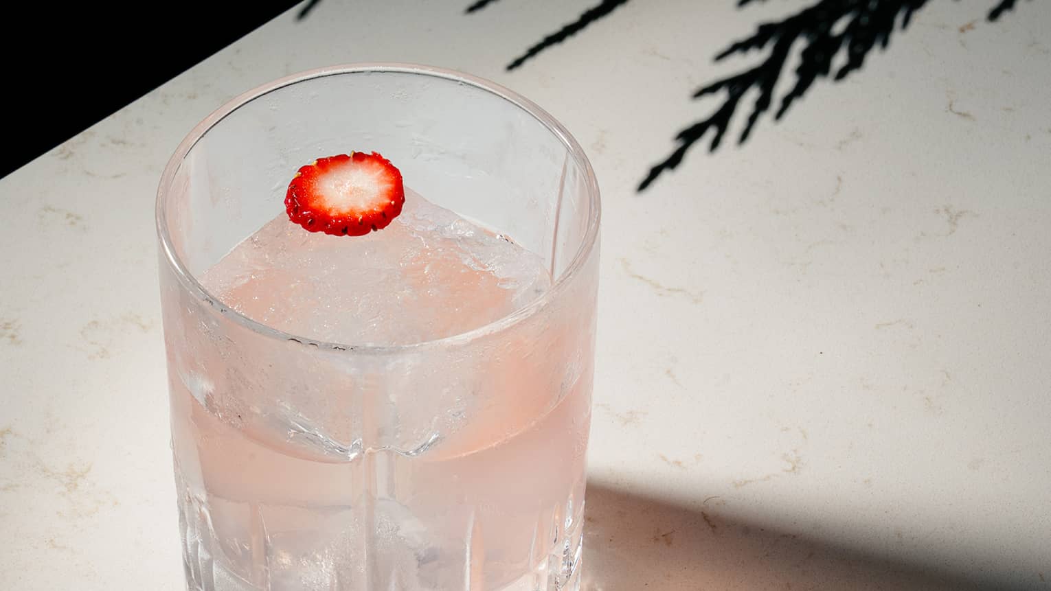 Vodka, strawberry, yogurt, Cocchi Rosa and peach cocktail served in a rocks glass and garnished with a sliver of strawberry