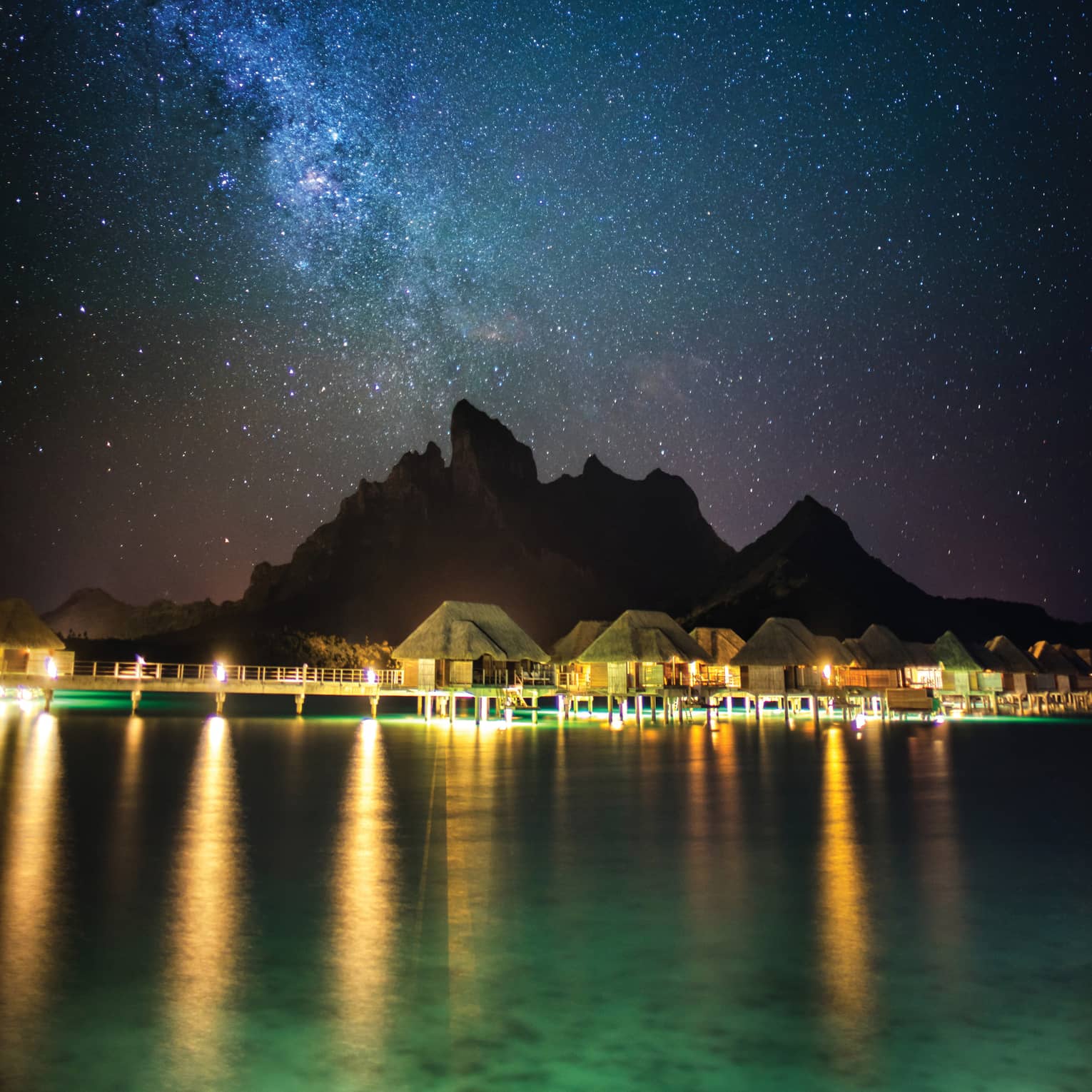 Illuminated Four Seasons Resort Bora Bora beneath a blanket of stars at night