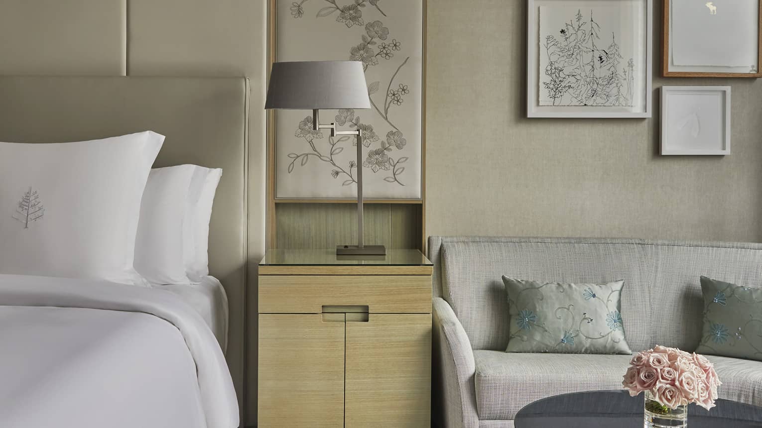 Guest room at Four Seasons Hotel Toronto, with light-coloured furniture, carpet, and walls. Glass coffee table with flowers.