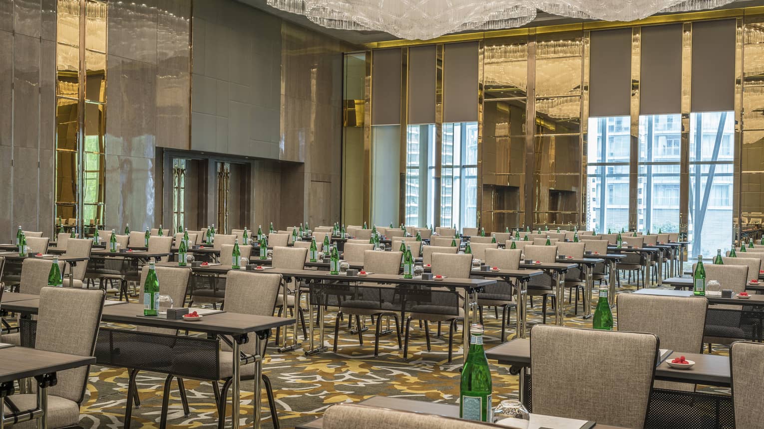 Rows of meeting tables with green water bottles in conference set up in ballroom