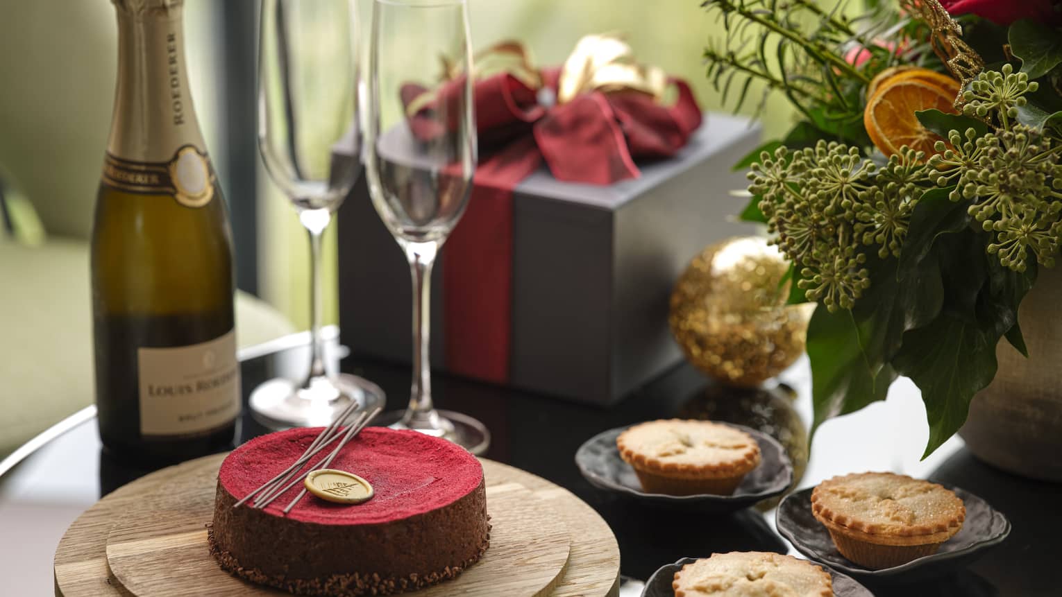 Close-up of holiday cake and three meat pies, plus Champagne bottle and two glasses