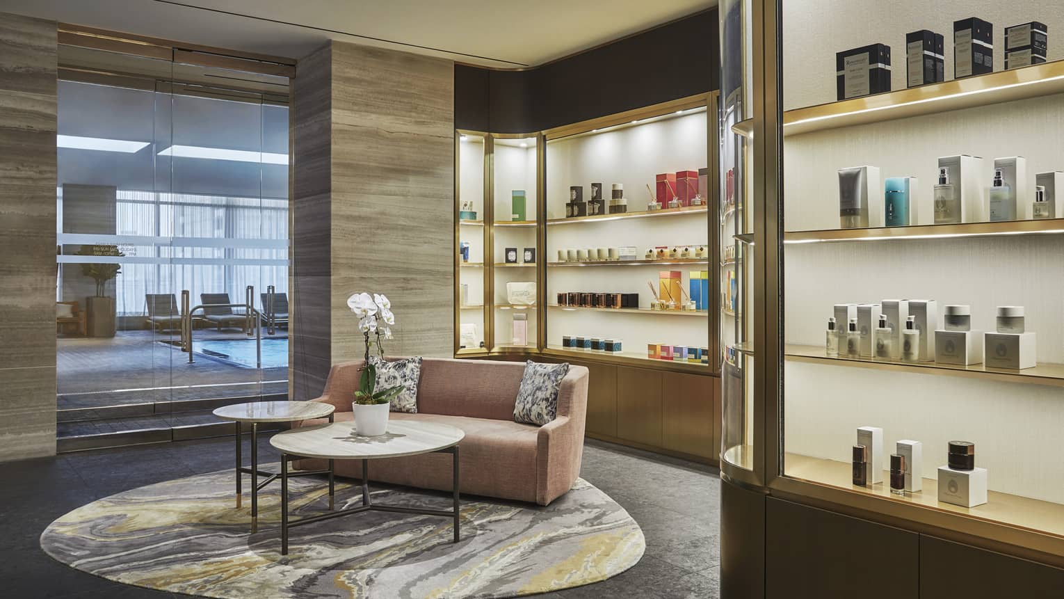 A pink loveseat sits in the centre of the lobby surrounded by illuminated products in showcases. 