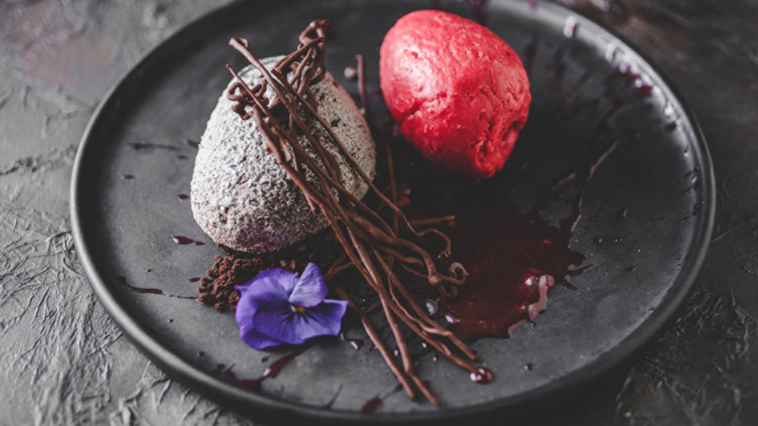 Several scoops of a frozen dessert topped with chocolate