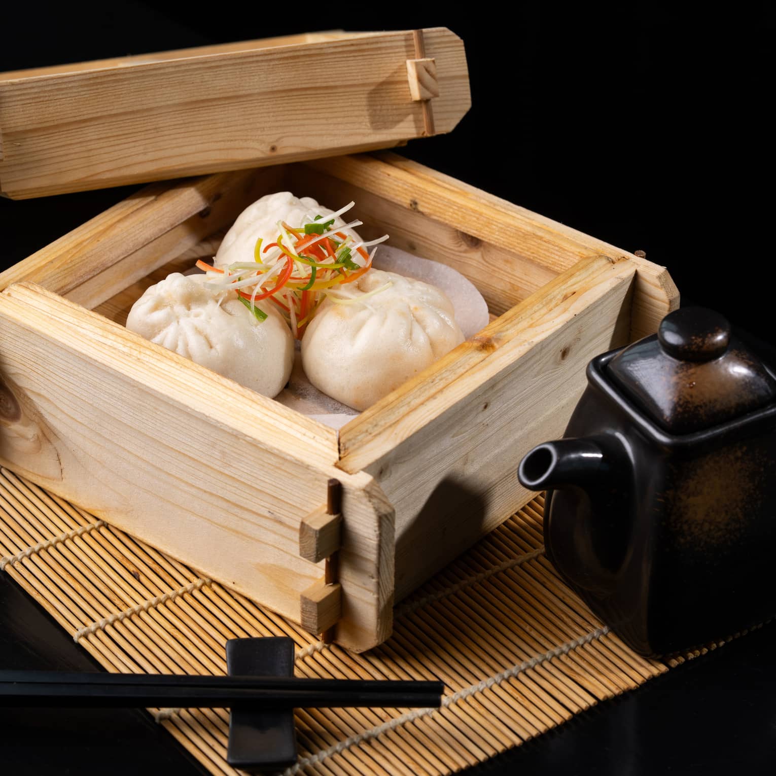Steamed buns served in a bamboo tray with chopsticks