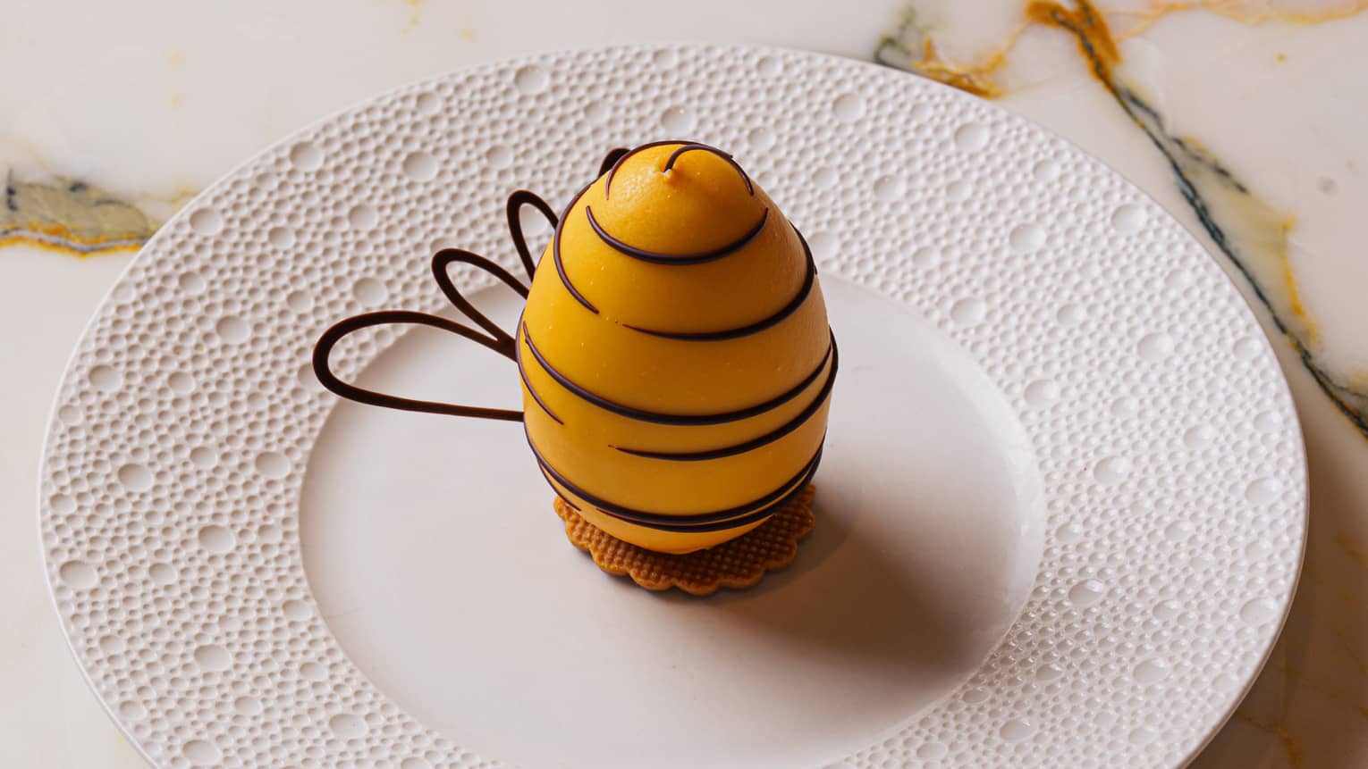 Dessert shaped like a honey bee served on a white round plate