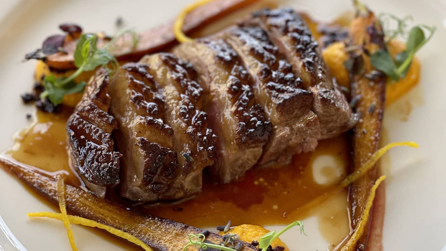 Duck breast with orange glaze, carrot pur�e and lavender served on a white plate