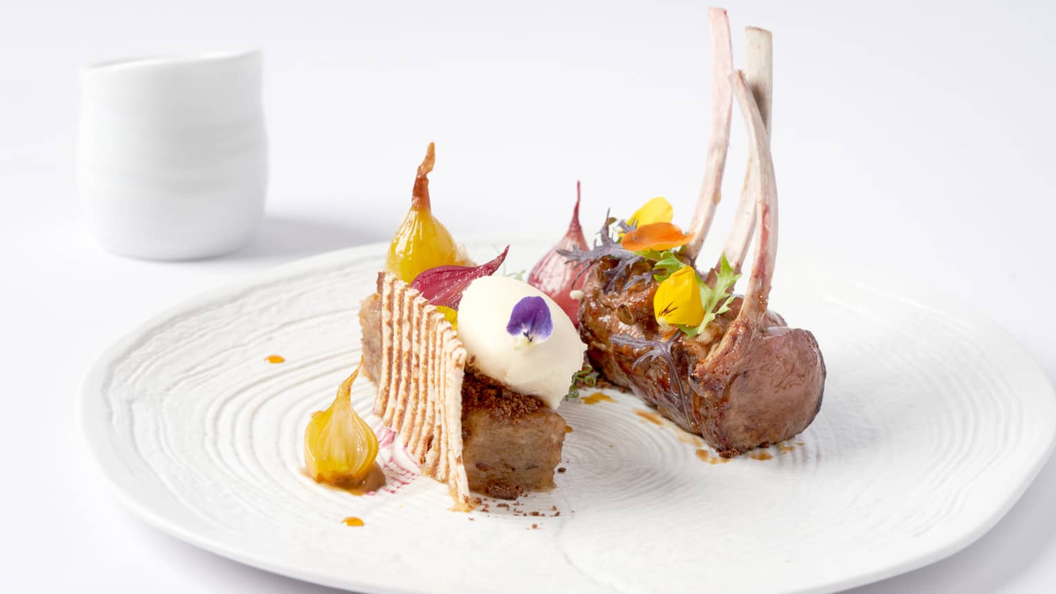 Gourmet rack of lamb topped with candied yellow beets, flowers