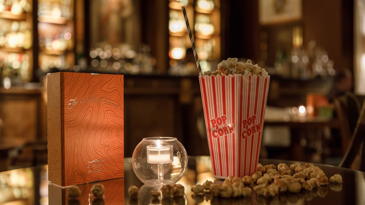 Warmly lit table with movie popcorn and tealight candle.