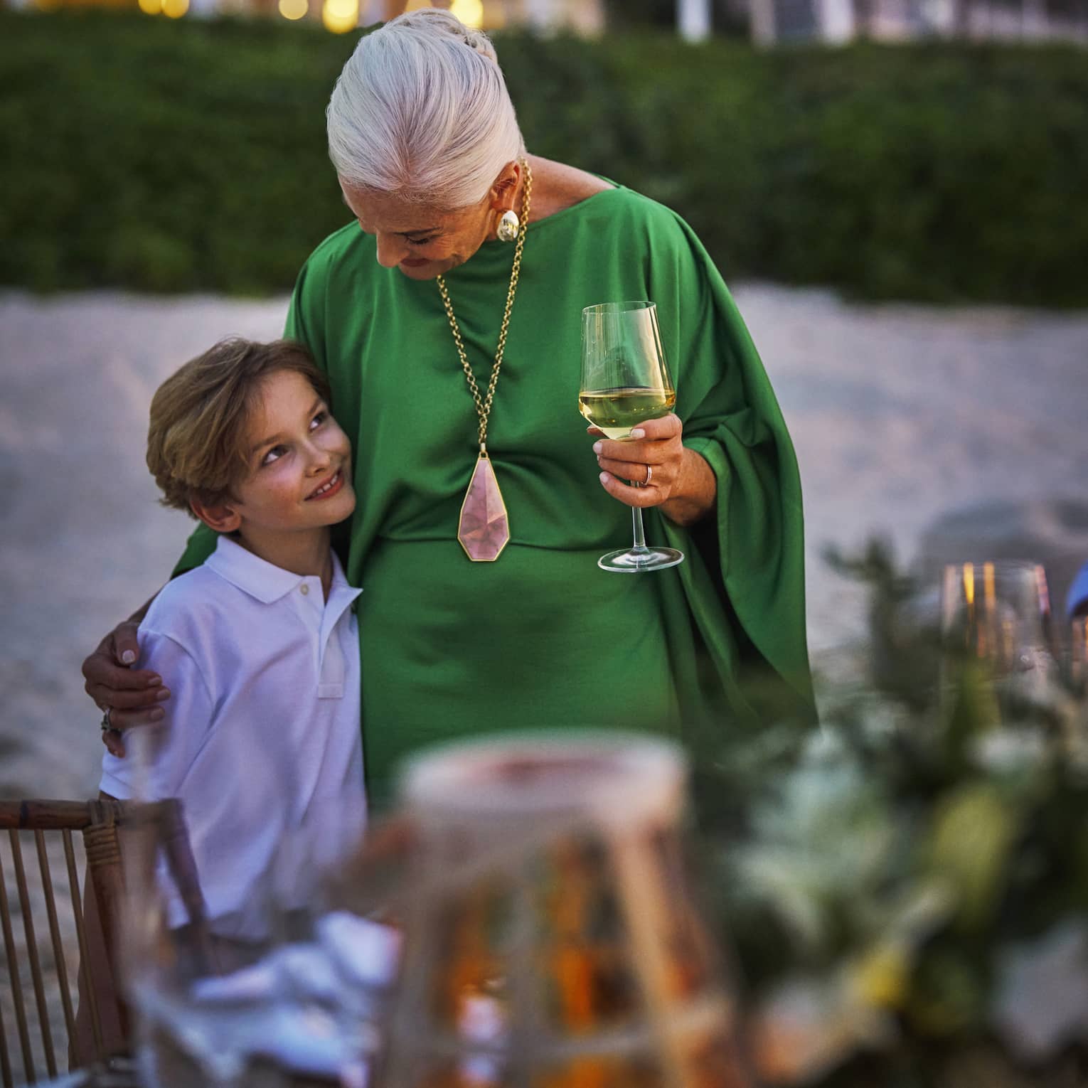 Grandmother and child hug next to a private dining table set on the beach